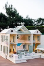 Handcrafted wooden dollhouse with miniature furniture and details, displayed in a minimal setting.