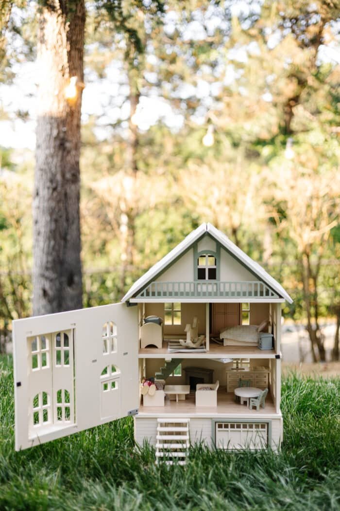 Victorian-style handcrafted white wooden dollhouse by Little Forest Animals, photographed outdoors on green grass in natural light.