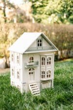 Victorian-style handcrafted white wooden dollhouse by Little Forest Animals, photographed outdoors on green grass in natural light.