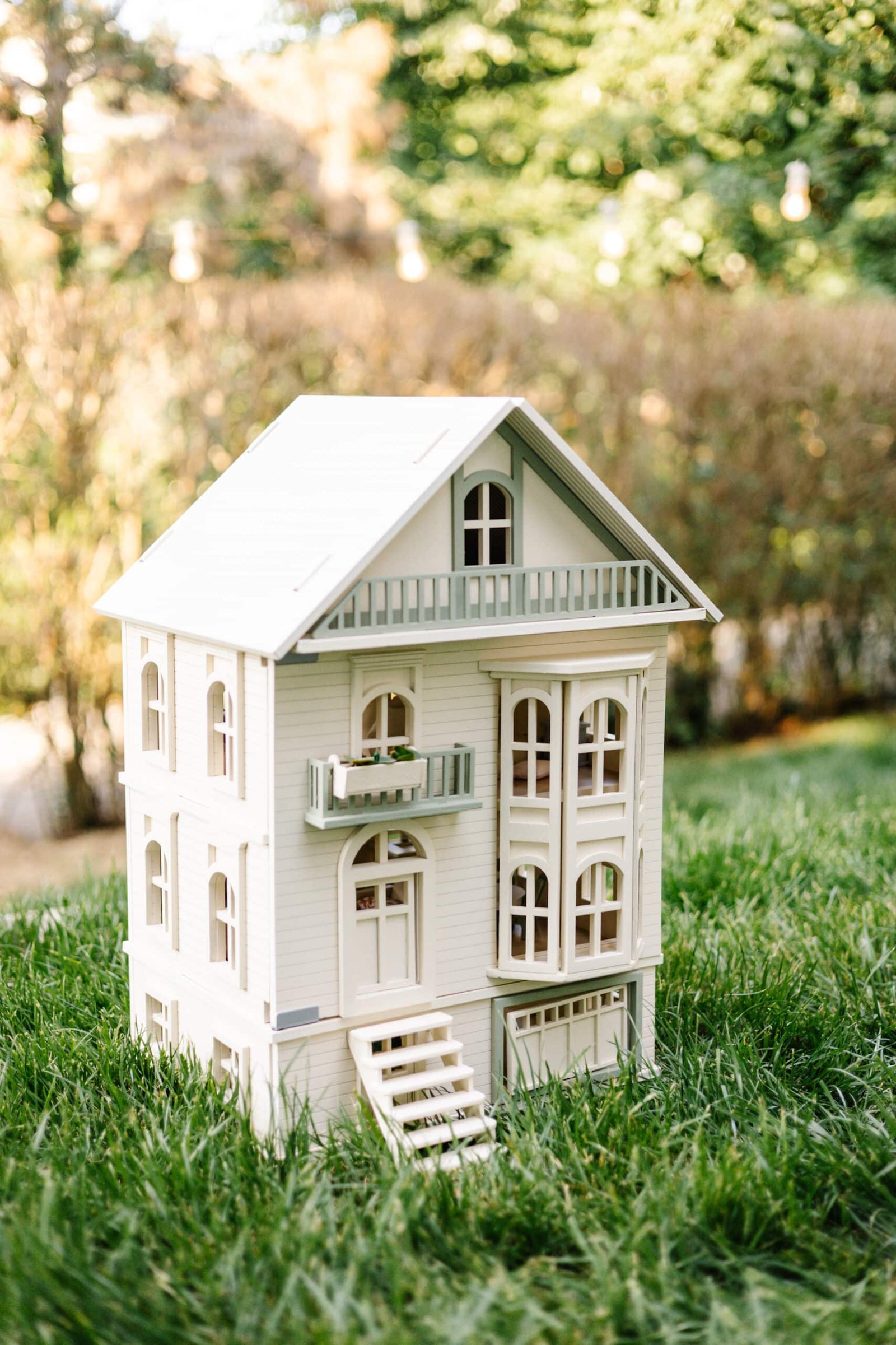 Victorian Wooden Dollhouse | Handcrafted by Little Forest Animals Victorian-style handcrafted white wooden dollhouse by Little Forest Animals, photographed outdoors on green grass in natural light.