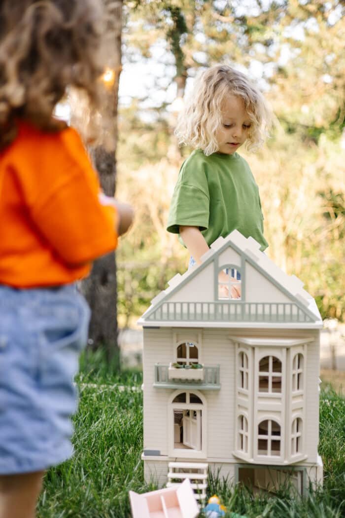 Victorian-style handcrafted white wooden dollhouse by Little Forest Animals, photographed outdoors on green grass in natural light.