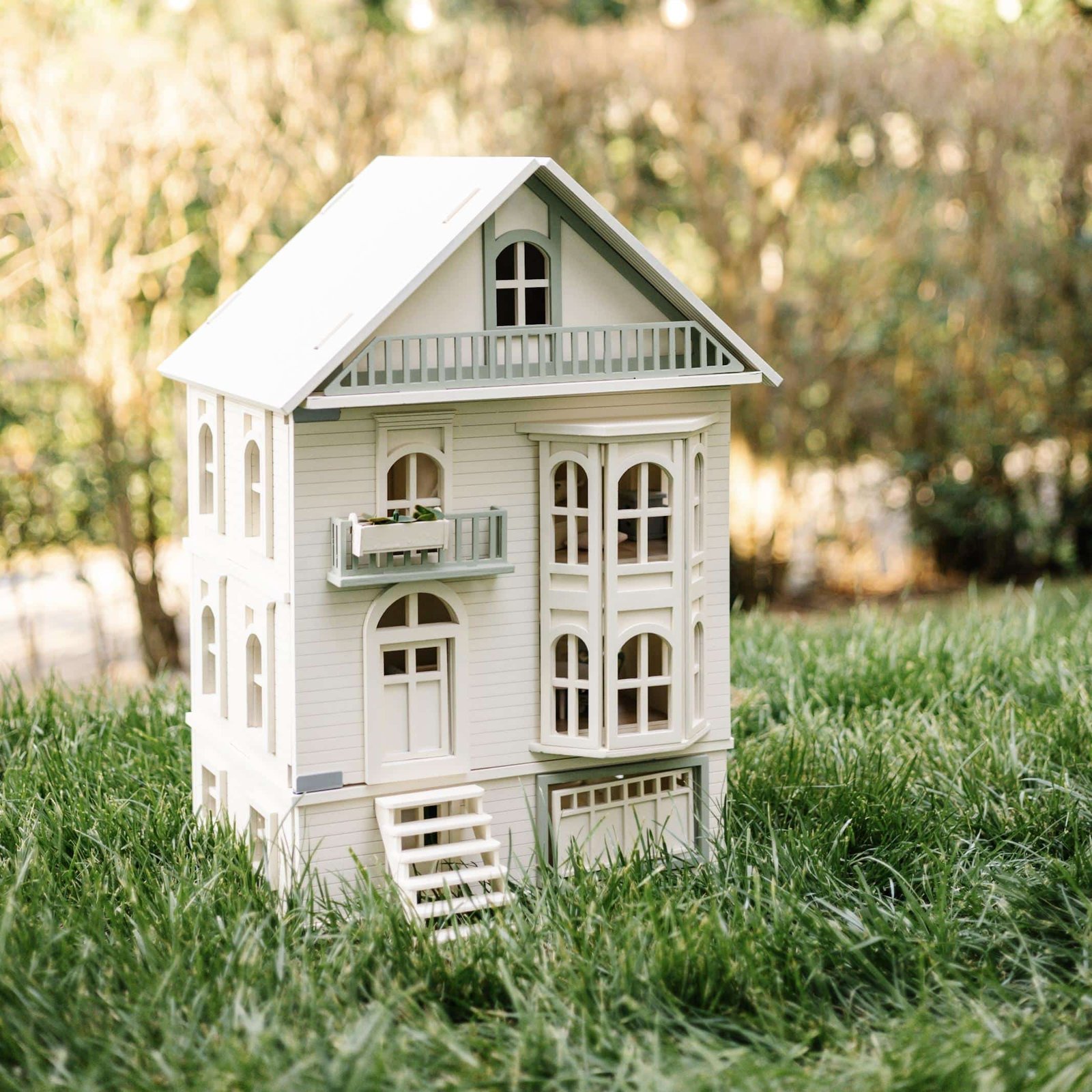 Victorian Wooden Dollhouse | Handcrafted by Little Forest Animals Victorian-style handcrafted white wooden dollhouse by Little Forest Animals, photographed outdoors on green grass in natural light.
