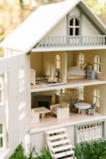 Victorian-style handcrafted white wooden dollhouse by Little Forest Animals, photographed outdoors on green grass in natural light.