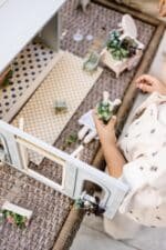 Miniature wooden flower shop dollhouse in pastel blue, with plants, a bunny figure, and charming outdoor details.